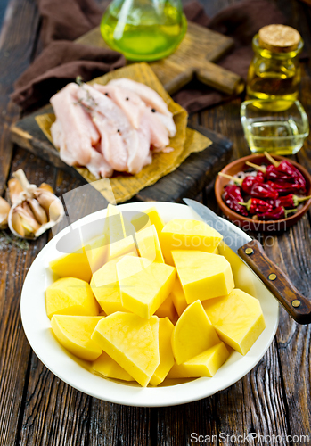 Image of raw potato and chicken on wooden table
