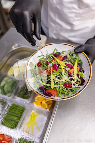 Image of Professional chef adding final touches to a vibrant salad