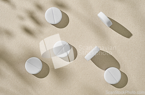 Image of white pills on beige background