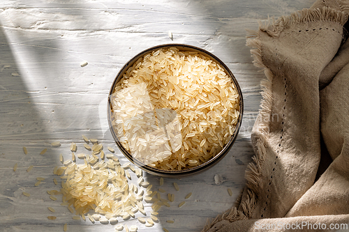 Image of bowl of raw rice on white sunny rustic kitchen table