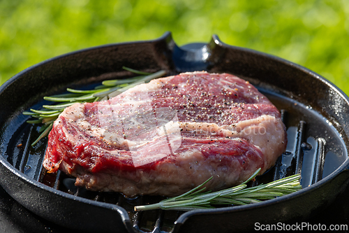 Image of raw beef steak with pepper on grill pan