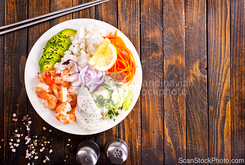 Image of Poke bowl and ingredients on wooden table,
