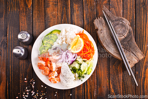 Image of Poke bowl and ingredients on wooden table,