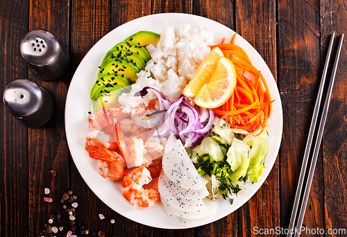 Image of Poke bowl and ingredients on wooden table,