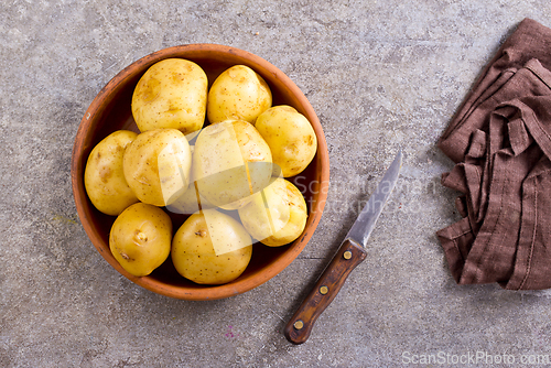 Image of bowl with raw potatoes on a table