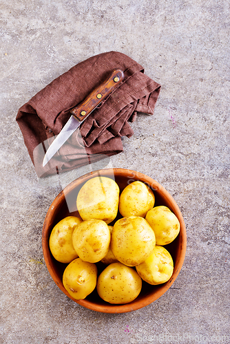 Image of bowl with raw potatoes on a table