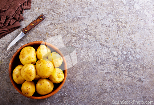 Image of bowl with raw potatoes on a table