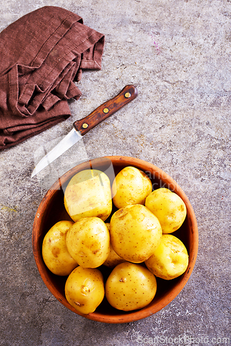 Image of bowl with raw potatoes on a table