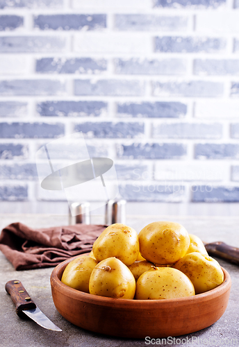 Image of bowl with raw potatoes on a table