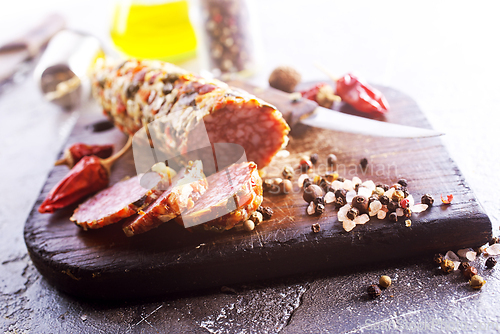 Image of Traditional smoked salami sausage on wooden board. Slices of sausage in motion.