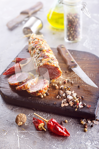 Image of Traditional smoked salami sausage on wooden board. Slices of sausage in motion.
