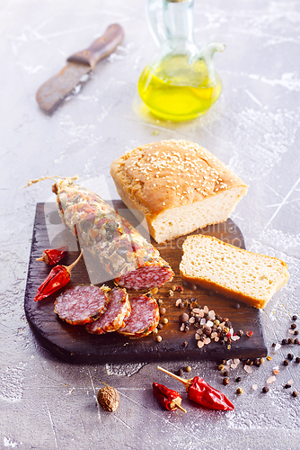 Image of Traditional smoked salami sausage on wooden board. Slices of sausage in motion.