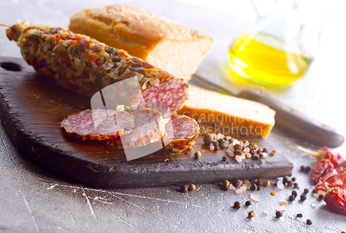 Image of Traditional smoked salami sausage on wooden board. Slices of sausage in motion.