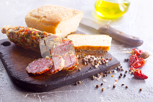 Image of Traditional smoked salami sausage on wooden board. Slices of sausage in motion.