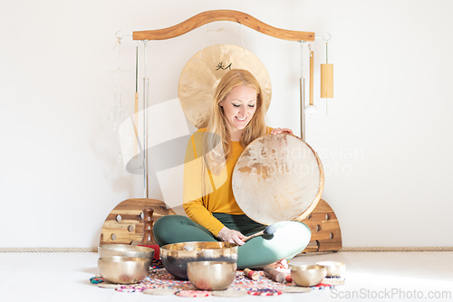 Image of Young cheerful woman performing music therapy session with traditional instruments. Sound meditation, body healing. Seven chakras. Healthcare recreation process.