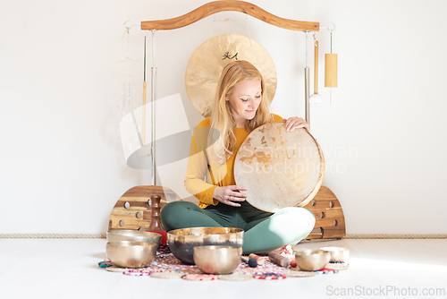 Image of Young cheerful woman performing music therapy session with traditional instruments. Sound meditation, body healing. Seven chakras. Healthcare recreation process.