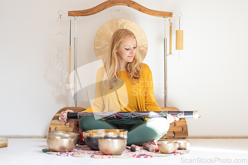 Image of Young cheerful woman performing music therapy session with traditional instruments. Sound meditation, body healing. Seven chakras. Healthcare recreation process.