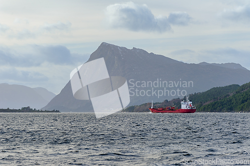Image of Majestic Norwegian landscapes with a cargo ship sailing through 