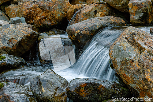 Image of Flowing water cascades over textured rocks amidst Norway's seren