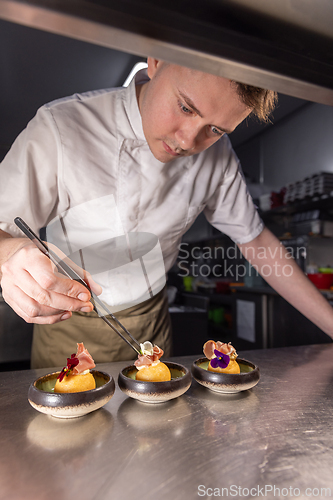 Image of Professional chef carefully placing edible flowers