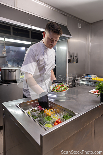 Image of Chef using tongs and holding plate