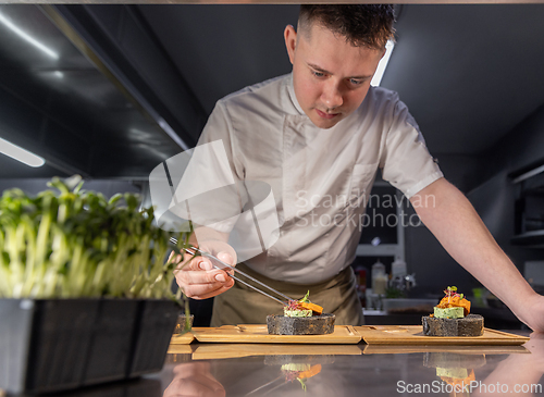 Image of Professional chef carefully preparing gourmet black bread canape