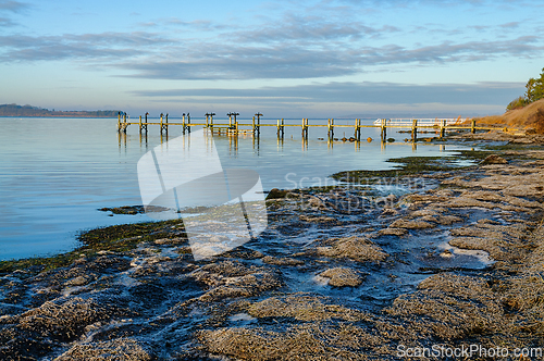 Image of Tranquil morning at the coastal pier with calm waters reflecting