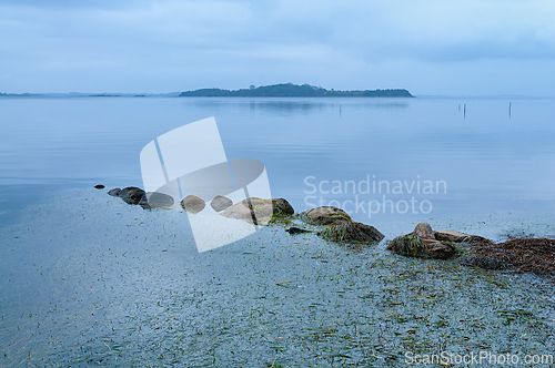 Image of Peaceful waters reflect soft blue hues at a tranquil lakeside in
