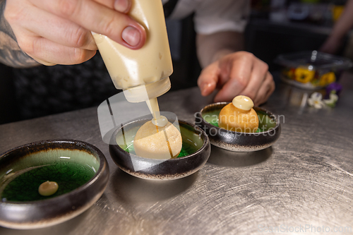 Image of Chef garnishing small round appetizers