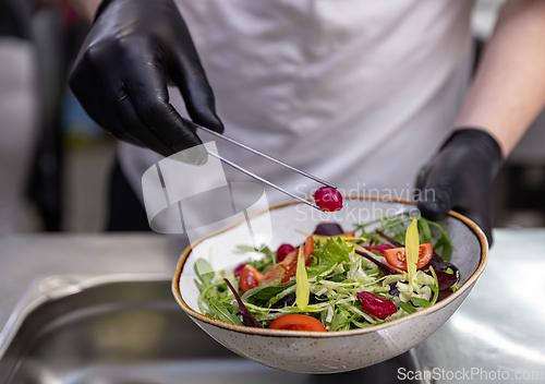 Image of Chef using tongs to add pickled onion