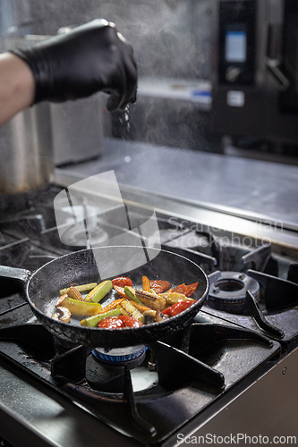 Image of Chef adding salt into a pan of grilled vegetables
