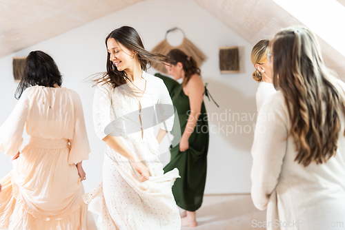 Image of Group of cheerful women all ages, happy people dancing together wearing traditional colorful dresses and hippy clothes. Free people enjoying leisure activity, emphasizing friendship, fun, movement.