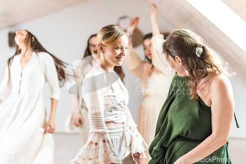 Image of Group of cheerful women all ages, happy people dancing together wearing traditional colorful dresses and hippy clothes. Free people enjoying leisure activity, emphasizing friendship, fun, movement.
