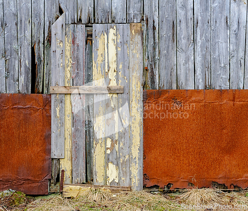 Image of Weathered barn door with peeling paint and rusted metal accents 