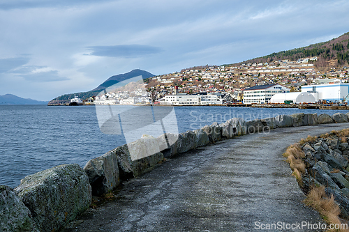 Image of Coastal pathway along the harbor in a serene town with hills and