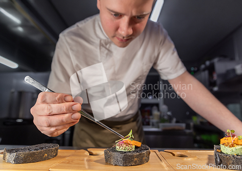 Image of Chef placing microgreens on gourmet black bread canapes