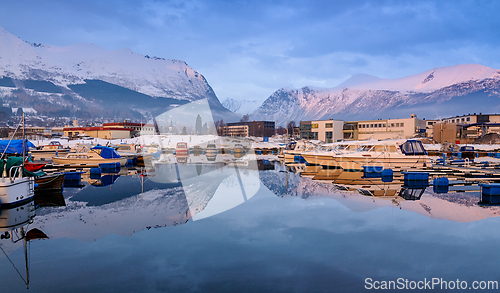 Image of Reflections of snowy mountains in serene harbor during early mor