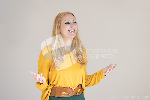Image of Portrait of confident beautiful woman with long blende hair, wearing casual clothes, standing in welcoming pose with open hands, meditating