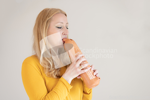 Image of Portrait of female musician playing on traditional clay flute. Woman playing ocarina.