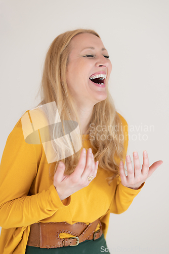 Image of Portrait of confident beautiful woman laughing, with long blende hair, wearing casual clothes, standing in welcoming pose with open hands, meditating