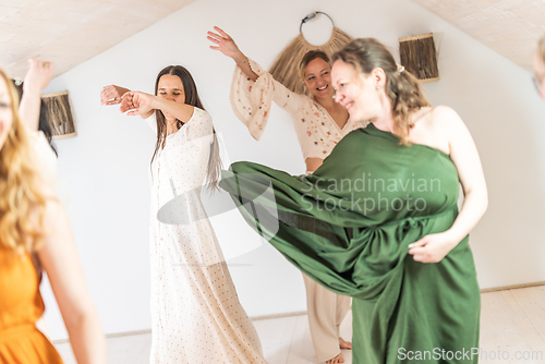 Image of Group of cheerful women all ages, happy people dancing together wearing traditional colorful dresses and hippy clothes. Free people enjoying leisure activity, emphasizing friendship, fun, movement.