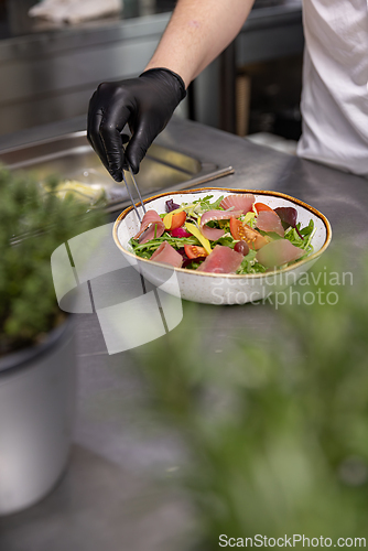 Image of Professional chef carefully preparing a gourmet salad