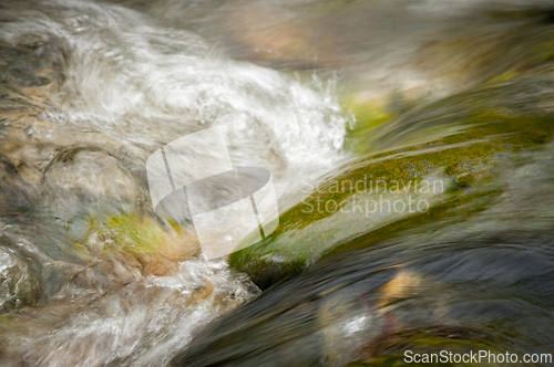Image of Flowing water cascades over smooth stones in a serene natural se