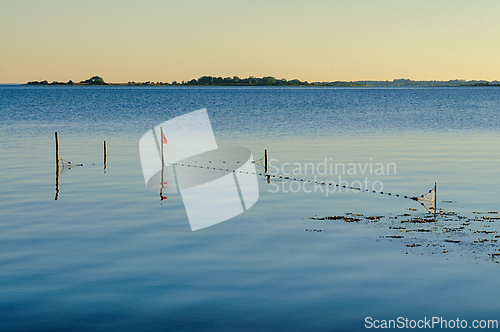 Image of Calm waters reflect sunlight as a peaceful fishing area appears 