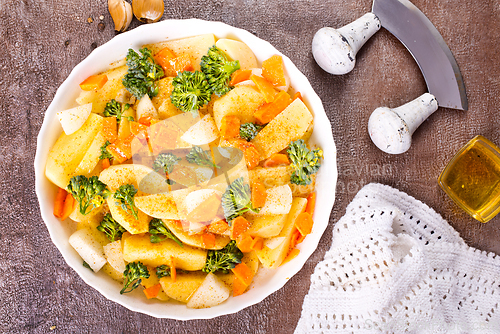 Image of Raw potatoes, garlic, onions, carrots in white bowl reading for cooking, mix vegetables