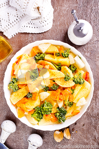 Image of Raw potatoes, garlic, onions, carrots in white bowl reading for cooking, mix vegetables