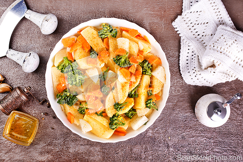 Image of Raw potatoes, garlic, onions, carrots in white bowl reading for cooking, mix vegetables