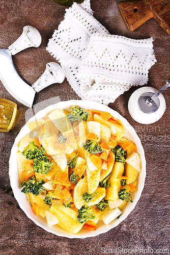 Image of Raw potatoes, garlic, onions, carrots in white bowl reading for cooking, mix vegetables