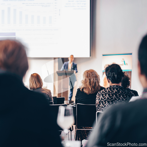 Image of Speaker giving a talk in conference hall at business event. Rear view of unrecognizable people in audience at the conference hall. Business and entrepreneurship concept.