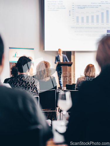 Image of Speaker giving a talk in conference hall at business event. Rear view of unrecognizable people in audience at the conference hall. Business and entrepreneurship concept.